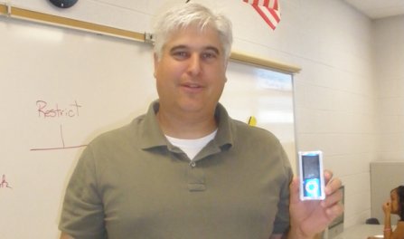 Reading Teacher Mark Mace poses with his iPod nano after winning the March Madness challenge.  Photo by Tricia Comfort