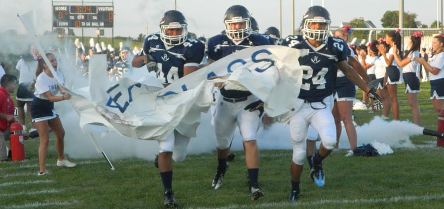 Seniors Campbell Rutherford, Isaiah Hertzler, and junior Luis Pinedo-Lafferty break through the banner at the E.C. Glass home game on August 29.