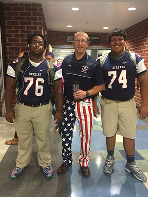 Players Quan Thomas (76) and Josh Soto (74) pose with principal Eric Miller before the game. 