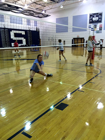 Junior Athena Benton digs a hit while peppering with her partner.