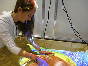 FTC member Kayla Leaman moves sand around as the projector adjusts in real time to represent the topography of the sand.