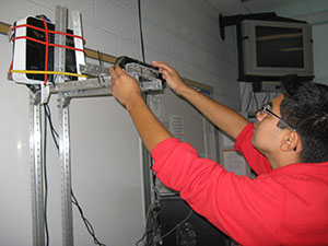 FTC Member Harrison Chicas works on the projector. As many hands worked in the sand box, the projector was offset and needed to be recalibrated.