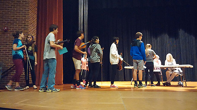 Violinists participating in Senior Regional Orchestra line up to receive their audition numbers. Afterwards, each person listened for their number to be called while they practiced in the Charlottesville High School auditorium.
