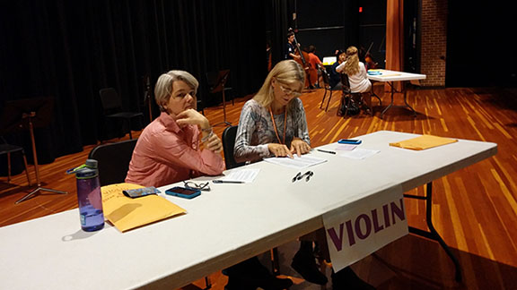 Parent volunteers Anne Knox (right) and Dekoven Pelton (left) of Charlottesville High School students help pass out audition numbers to violinists from all over the district. “We are helping to assign the audition numbers for the violin participants. We have had 98 people so far and there could be 105. We started this morning at 8:00 am. [The hardest part about the job is] when the students don’t have the necessary paperwork, or there is a problem with their paperwork, and they have to wait for it to get sorted out,” Knox said.
