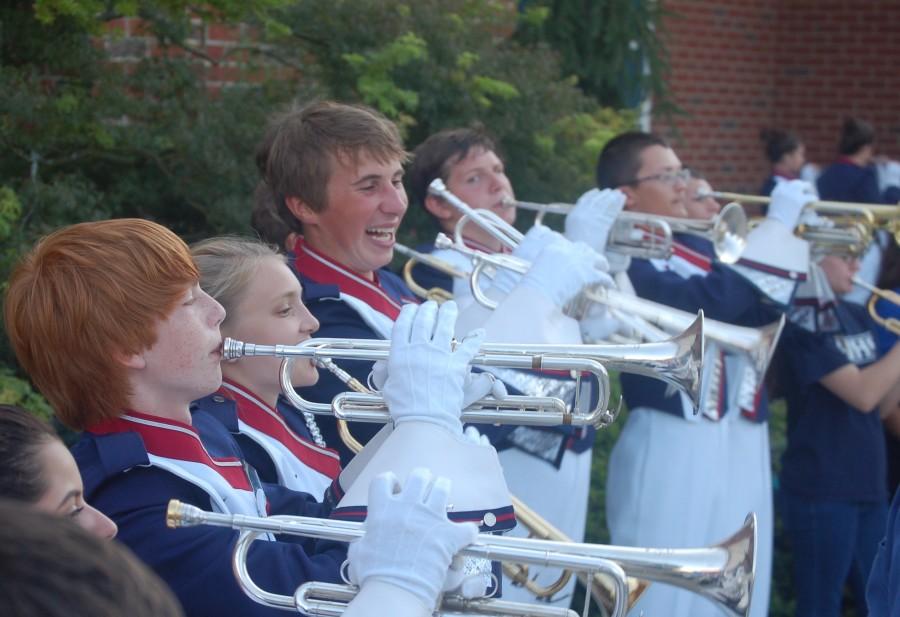 Members of the trumpet section participate in the warmup before the marching band performance at a friday night football game. 