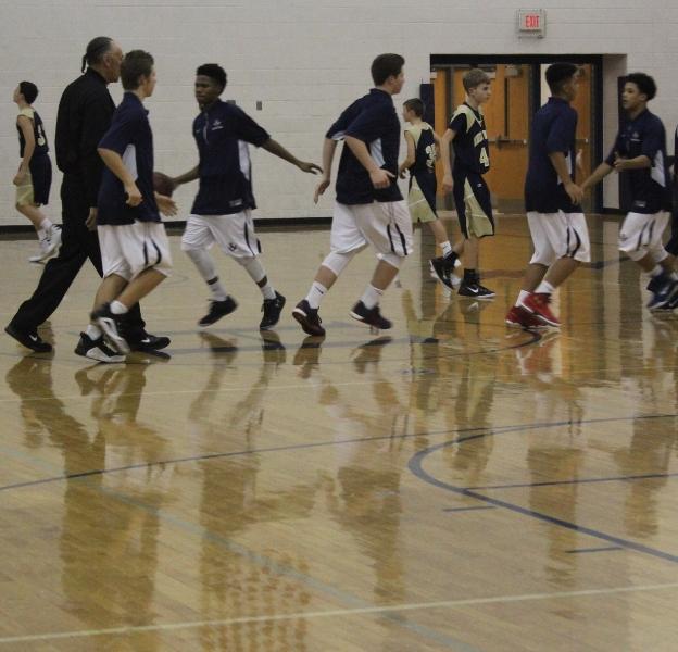 The JV basketball team runs out onto the court at the beginning of the game.
