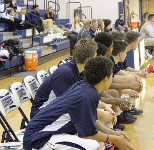 The players of the HHS JV basketball team sit on the sideline.