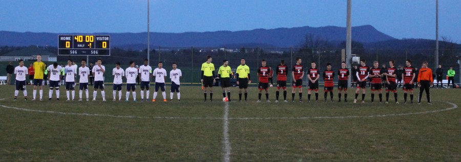 The Harrisonburg and Sherando boys varsity soccer teams line up at midfield for the national anthem prior to their matchup. 