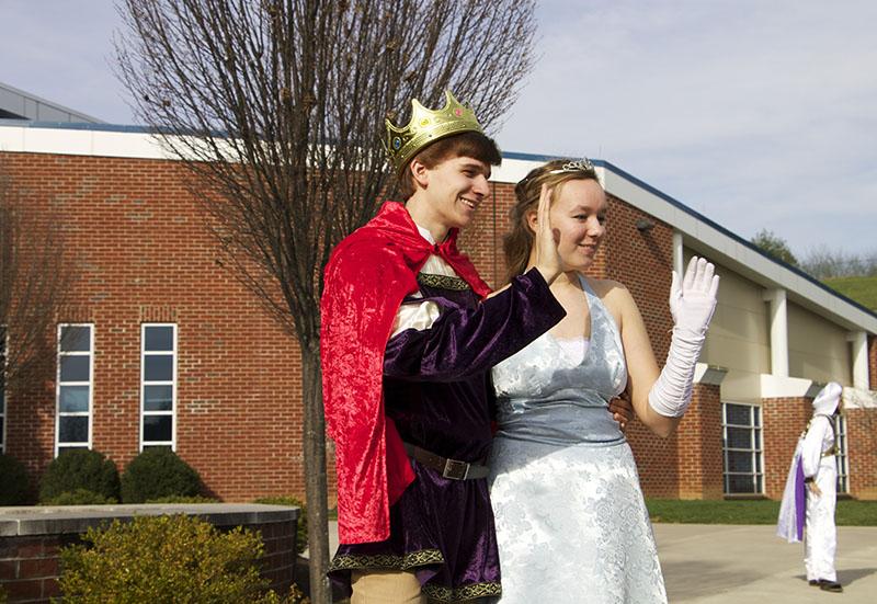 Senior Andy King (Prince Charming) and Junior Kennedy Wolter (Cinderella) wave as students get off of the buses. 