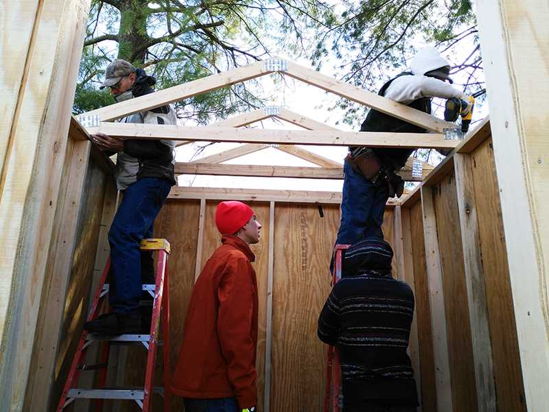 Nails+are+drilled+into+the+roof+while+students+help+with++the+ladders.