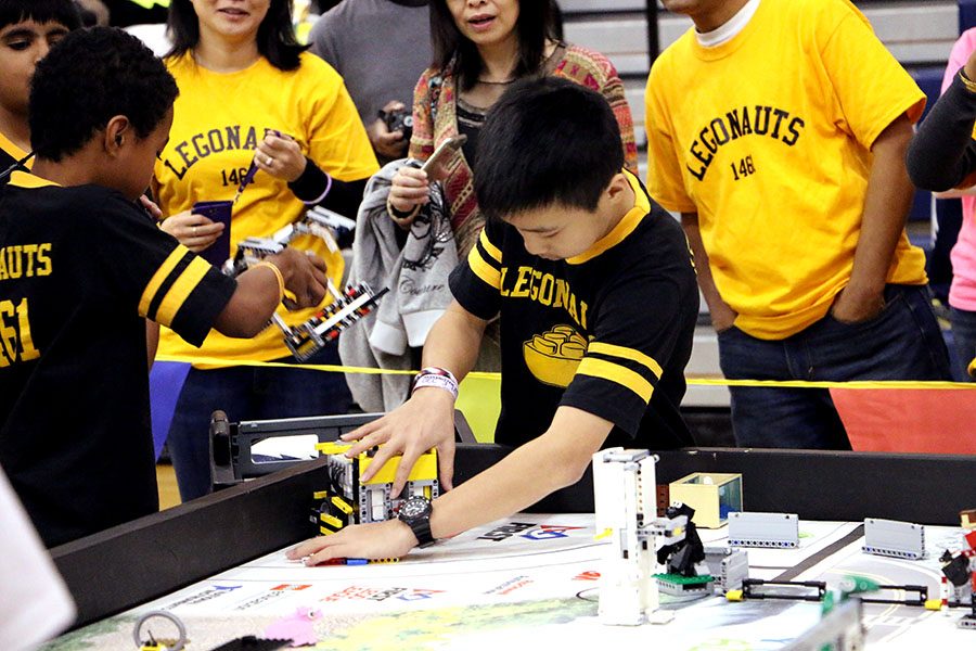 A Legonauts member works on the main body of the bot while his teammate goes to grab different parts. 