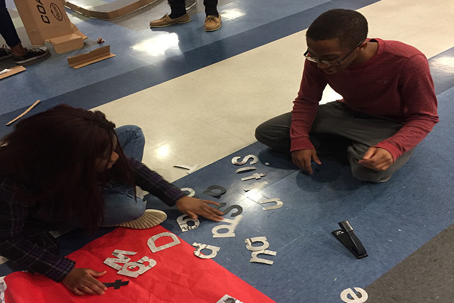 Senior Kyel Towler helps a classmate with the letters for their poster