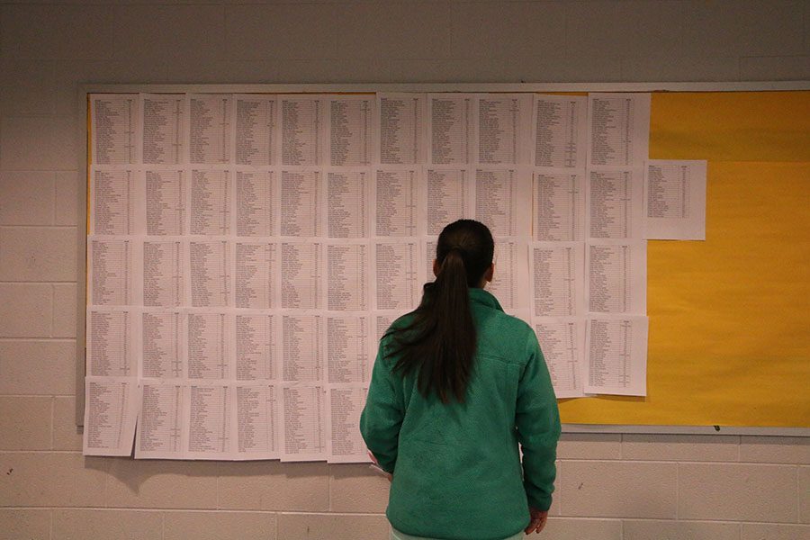 A student checks out their schedule from one of the lists along the wall in the school