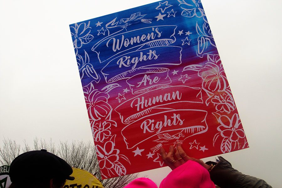 A sign is held up by a protestor supporting womens and human rights