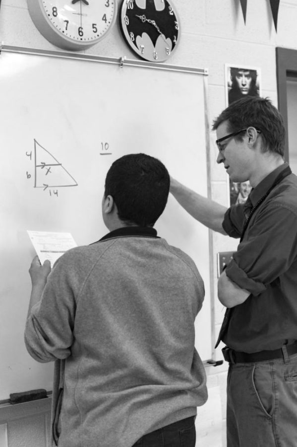 Norment instructs a student by solving problems on the board.