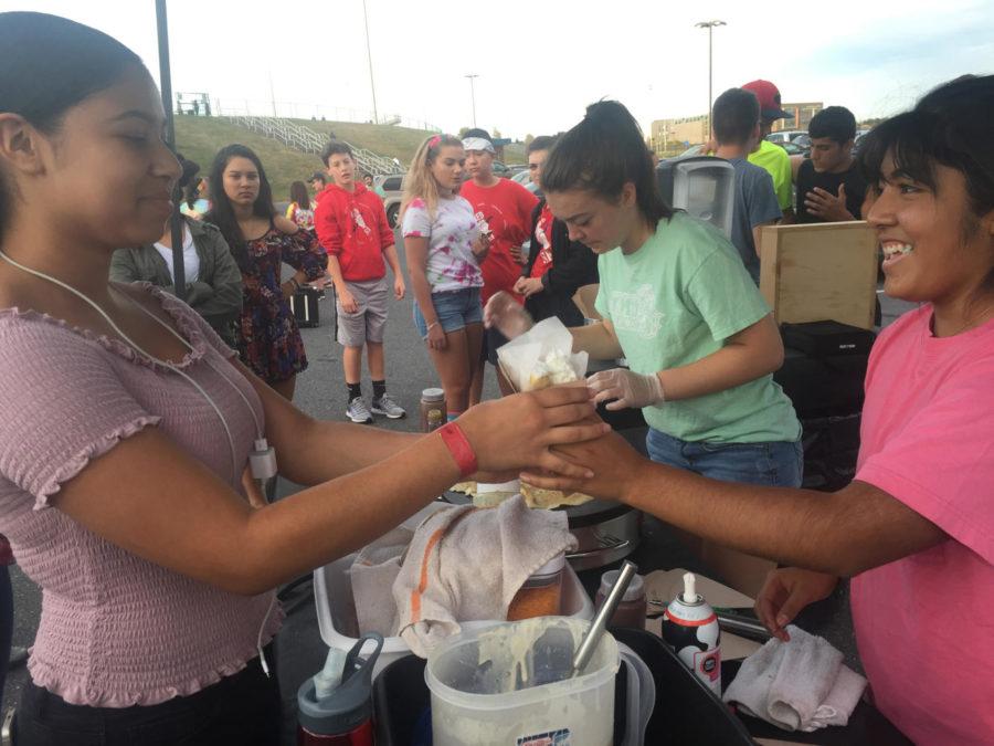 Senior Eva Didot serves a crepe to a student at the Red Sea tailgate.