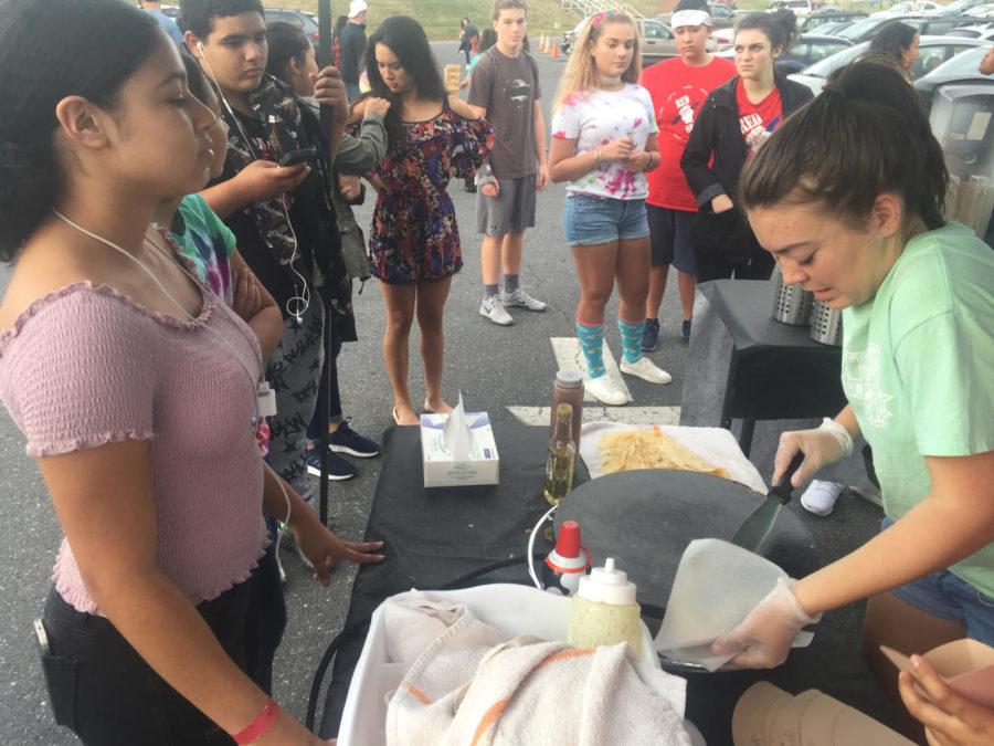 Senior Olivia Comer, Didot's helper at the stand, slides a crepe from the pan into the bag to be served. 