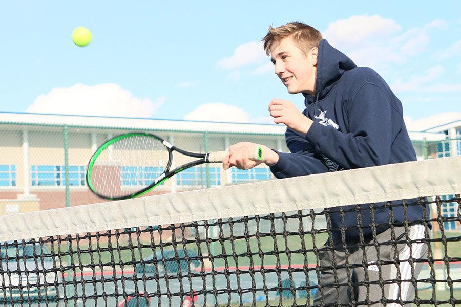 Sophomore Gabe Eshleman hits forehand volleys at the net.