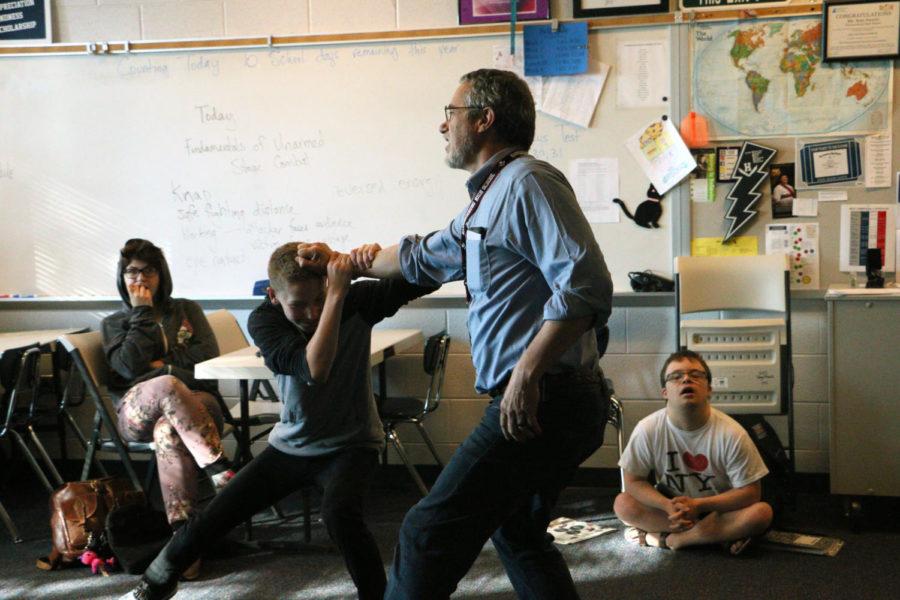 Musical director and drama teacher Stan Swartz exemplifies proper stage combat to his drama class with freshman Kai Johnson.