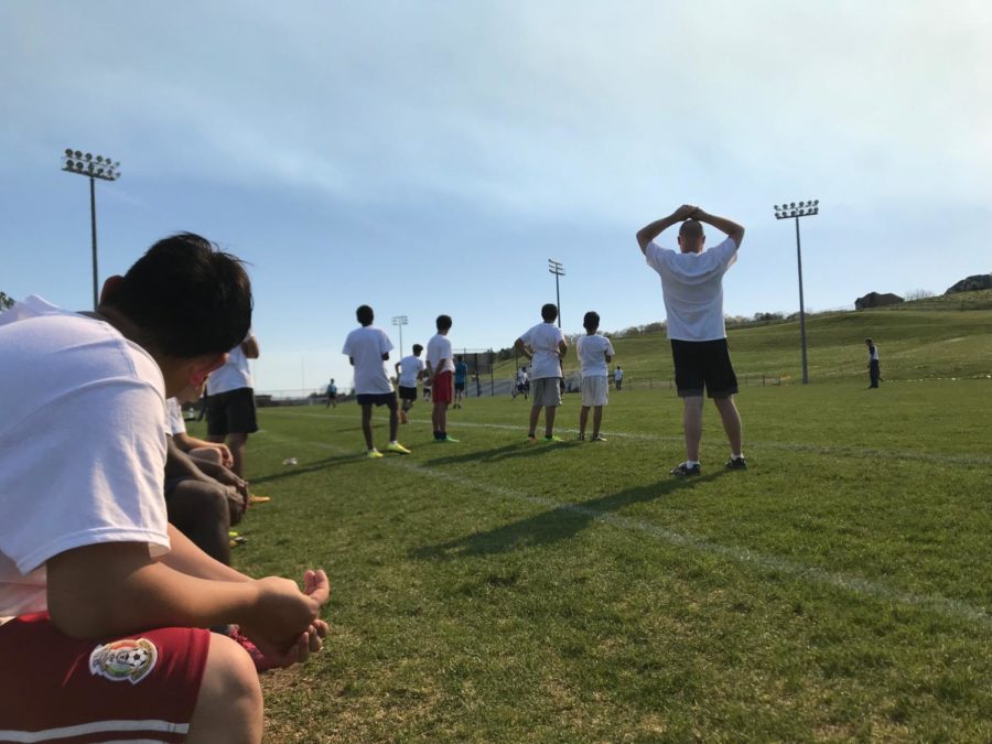 Thomas Harrison teammates and coach watch from the sideline.
