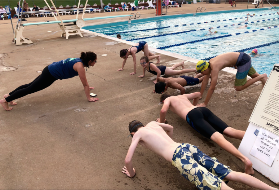 College coach and HHS graduate Hannah Daniel leads the swimmers in doing pushups during practice.