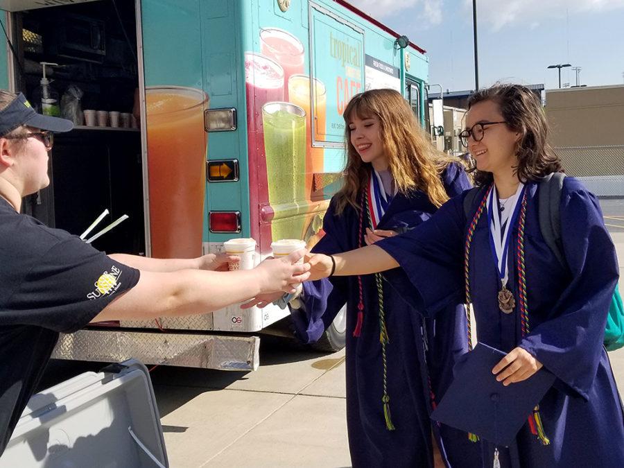 Seniors Alice Perrine (left) and Rose Copeland (right) grab free smoothies after taking their senior class picture. 