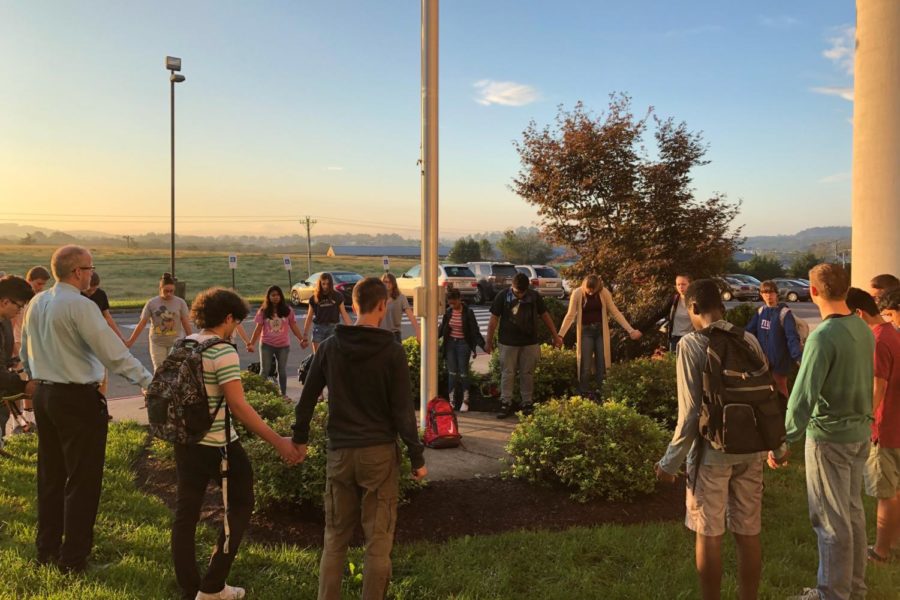 Students at the See You At The Pole event gather around the flagpole in a circle and pray. 