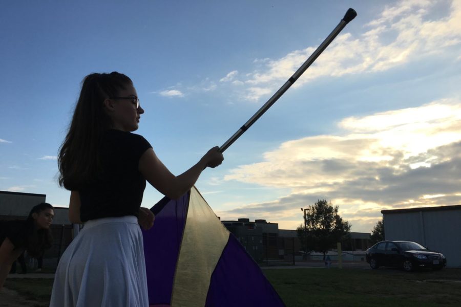 A color guard member twirls a flag before performing at the City County Showcase at Broadway High School.