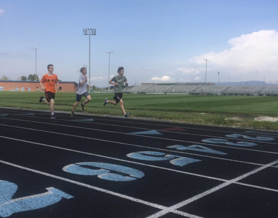 Boys cross country team practice by running around the track.
