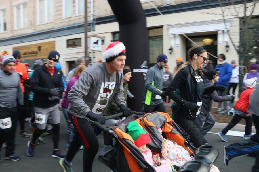 Runner #96 pushes two festive children across the start line, looking determined. 