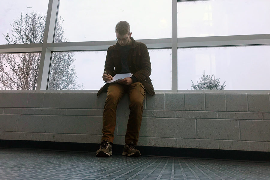 Senior Evan Wood sits at the window on a snowy day writing poetry. 