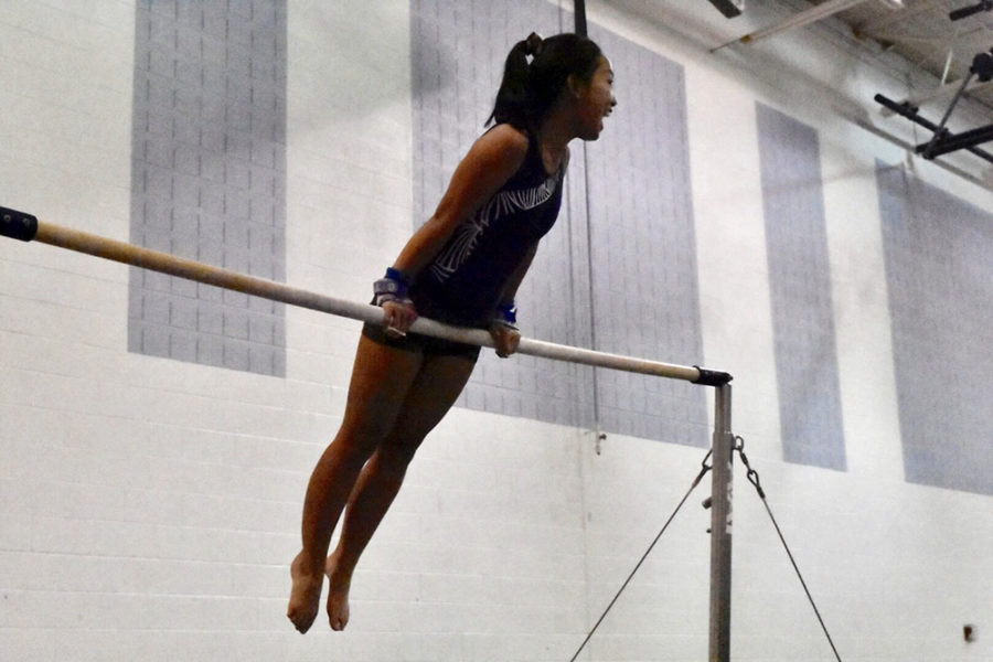 Sophomore Ruby Arndt smiles as she gets up to the high bar.
