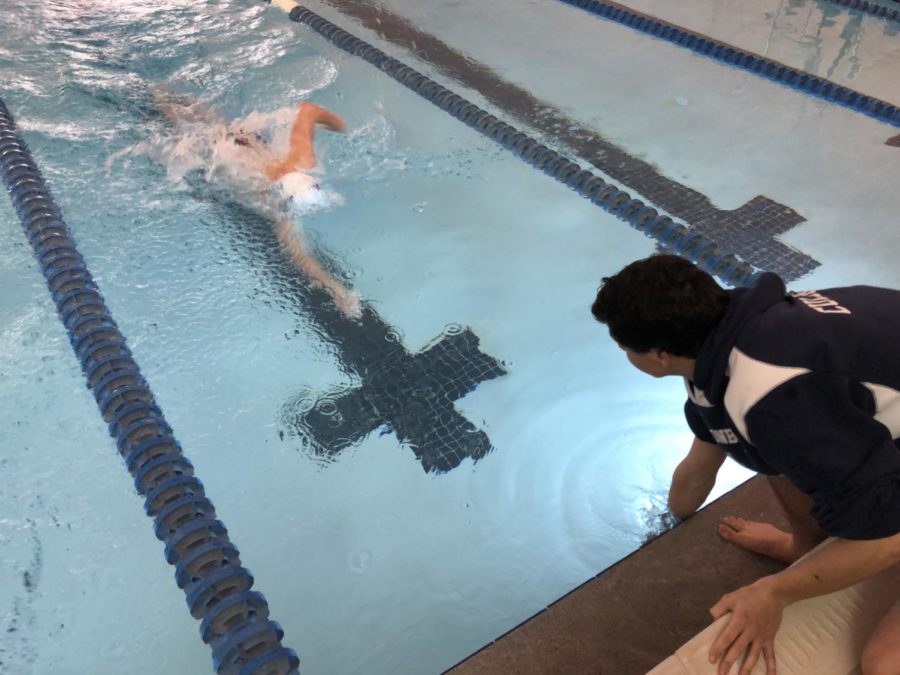 Junior Ritt Culbreth places a lap counter in the pool for senior James Henderson during the 500 yard freestyle event, which consists of 20 lengths. 