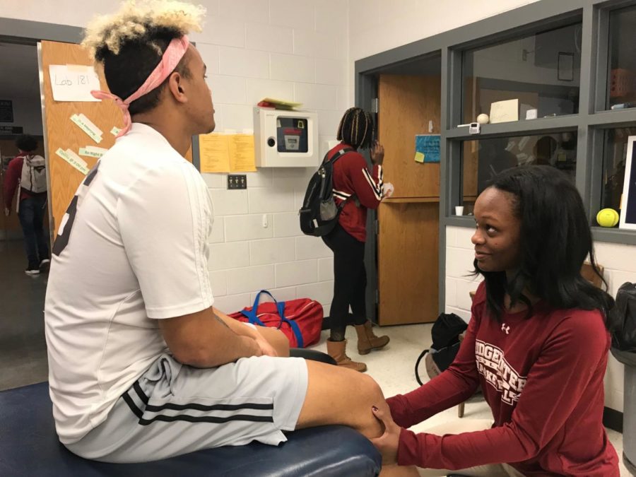Bridgewater College student and trainer intern at HHS athletics, Tyler Pinder, works with senior Micah Yutzy during indoor track season. After Pinder graduates college, she hopes to start working on her own with high school athletes and then work her way up to the college level. 