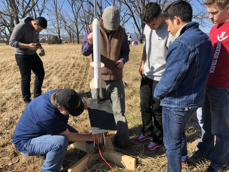 DE Engineering students being instructed on how to properly connect their rocket to the launch pad and ignition box.