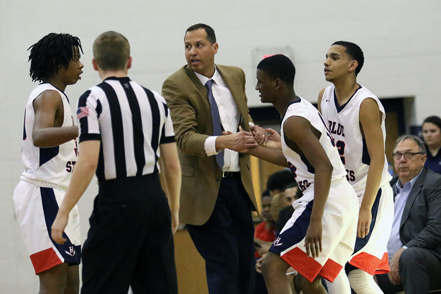 Coach Don Burgess helps seniors Taz Lockhart and Jakari Deaza up as they enter the game.