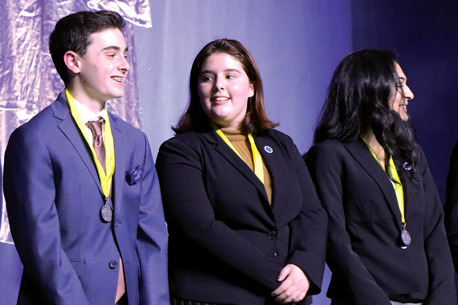 Junior Ann Diaz-Exposito (center) receives her medal for an outstanding test score. Diaz-Exposito is one of four DECA members who qualified for ICDC.