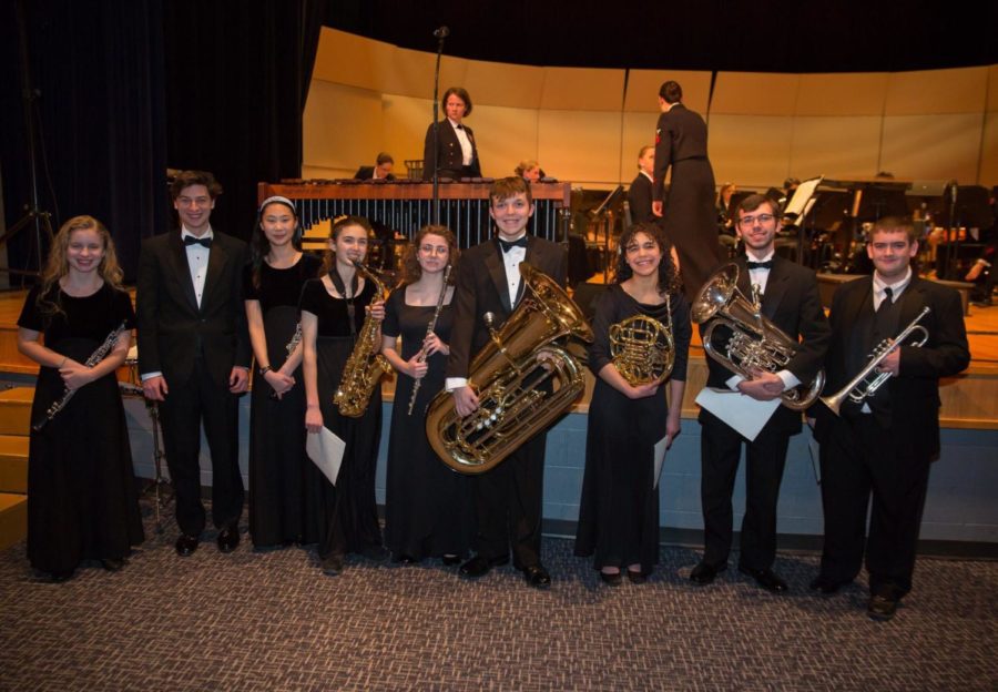 Nine students smile in excitement after performing with the Navy Band. 