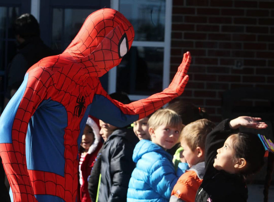 Junior Declan Leach as Spider-Man greets the line of elementary students with a high-five.