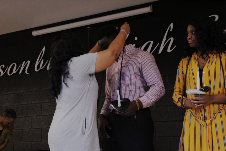 Advisor Cassandra Copeland gifts senior Pierre Mbala a black cord representing members commitment to the club.