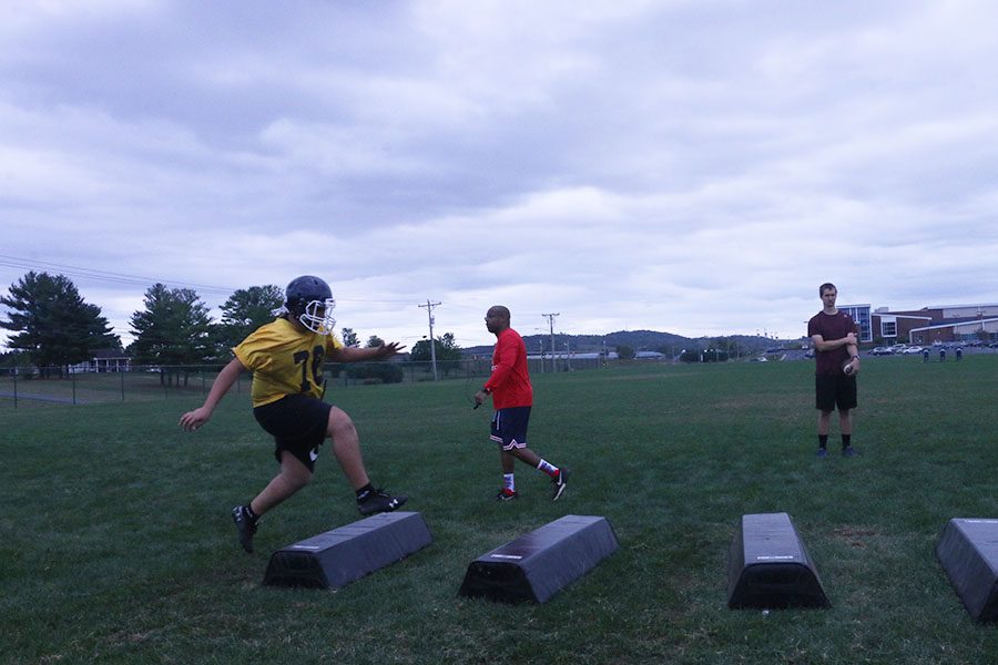 Coach Brian Austin critiques players as eighth grader Omari Faison starts the drill. 