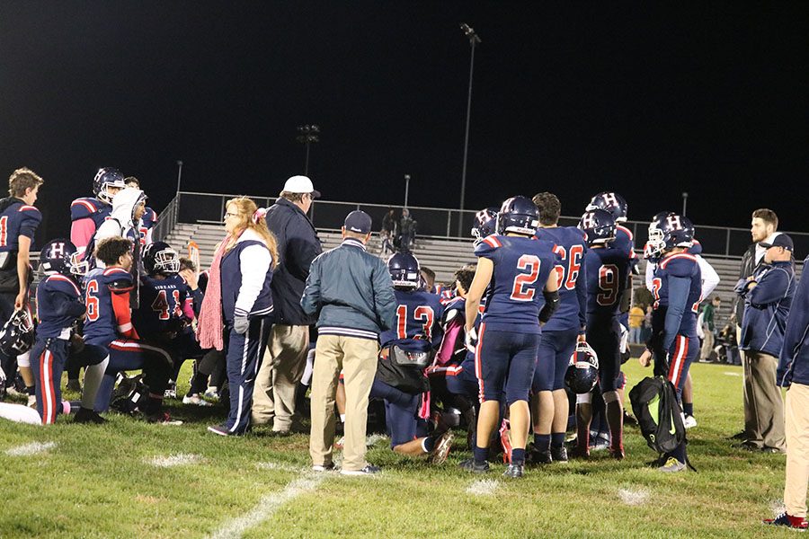 The Blue Streaks football team huddles up after the game to listen to what their coach has to say.
