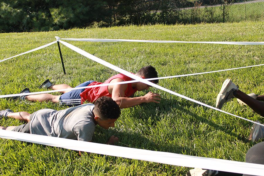 Cadet Command Sergeant Major senior Melvin Chicas and cadet Private First Class crawls under the tape for the team physical fitness course. 