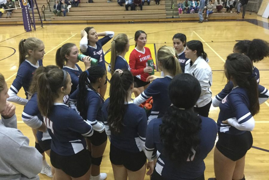 Varsity volleyball takes a time out and huddles up.
