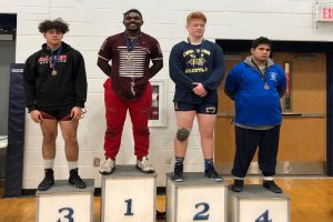 Junior Antwonne Washington stands on podium as the first place winner of a wrestling meet. Washington previously won at the Sophomore State Competition for wrestling as a sophomore. 