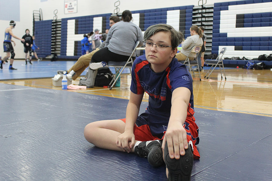 Freshman Scott Lambert stretches before a wrestling match. Wrestling involves a lot of physical strain for Lambert. “My favorite part is that even though you are competing individually, the team is one family,” Lambert said. “[The hardest part is] how much physical training it takes to wrestle.”