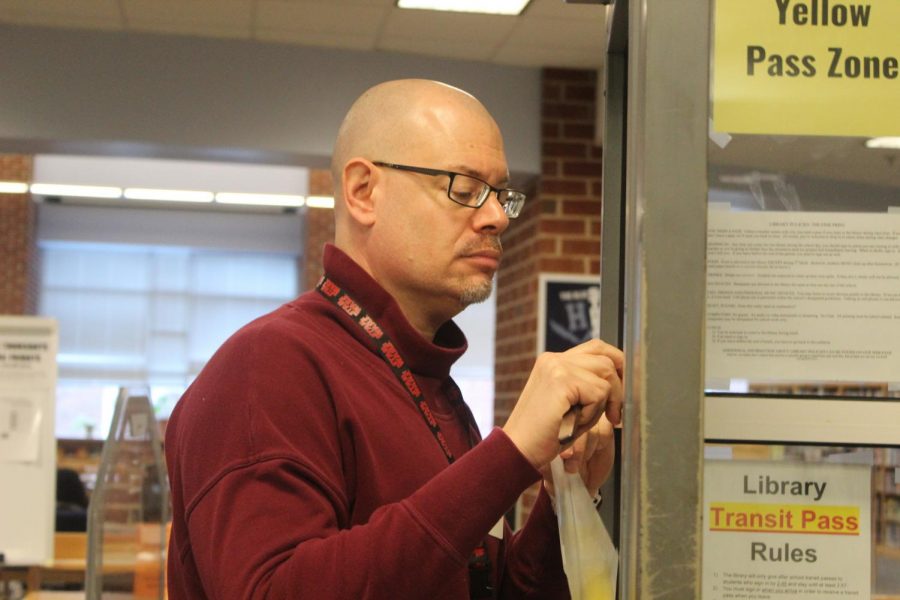 Library secretary Bradley Walton cleans up the tape on the door to the library. 