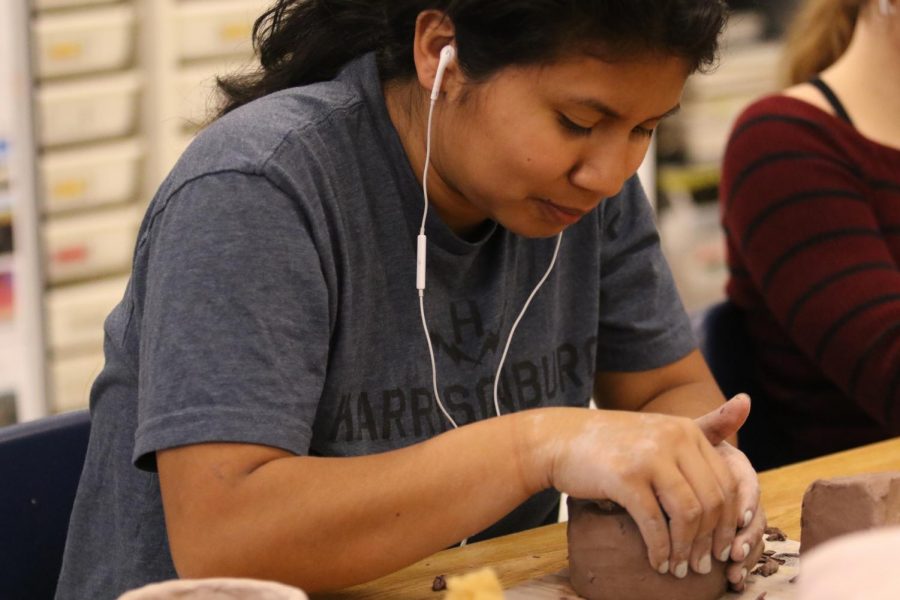 Senior Jennifer Arteaga molds her pot for a ceramics project while listening to music.