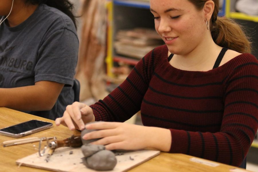 Senior Paula Rivera works on sculpting and contracting her clay into a pot.