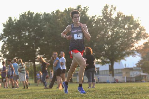 Spectators watch as junior David Beck strides to the finish line at the Rockingham County Fairgrounds. Out of 15 teams, Harrisonburg placed second behind Spotswood Sept. 11.